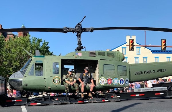 Vietnam-era Huey helicopter with US Armed Forces seal decals and veterans seated inside